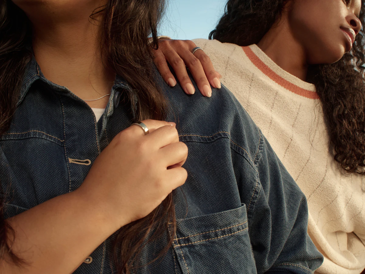 Two people standing side by side outdoors, one resting a hand on the other's shoulder, both wearing Oura Rings.