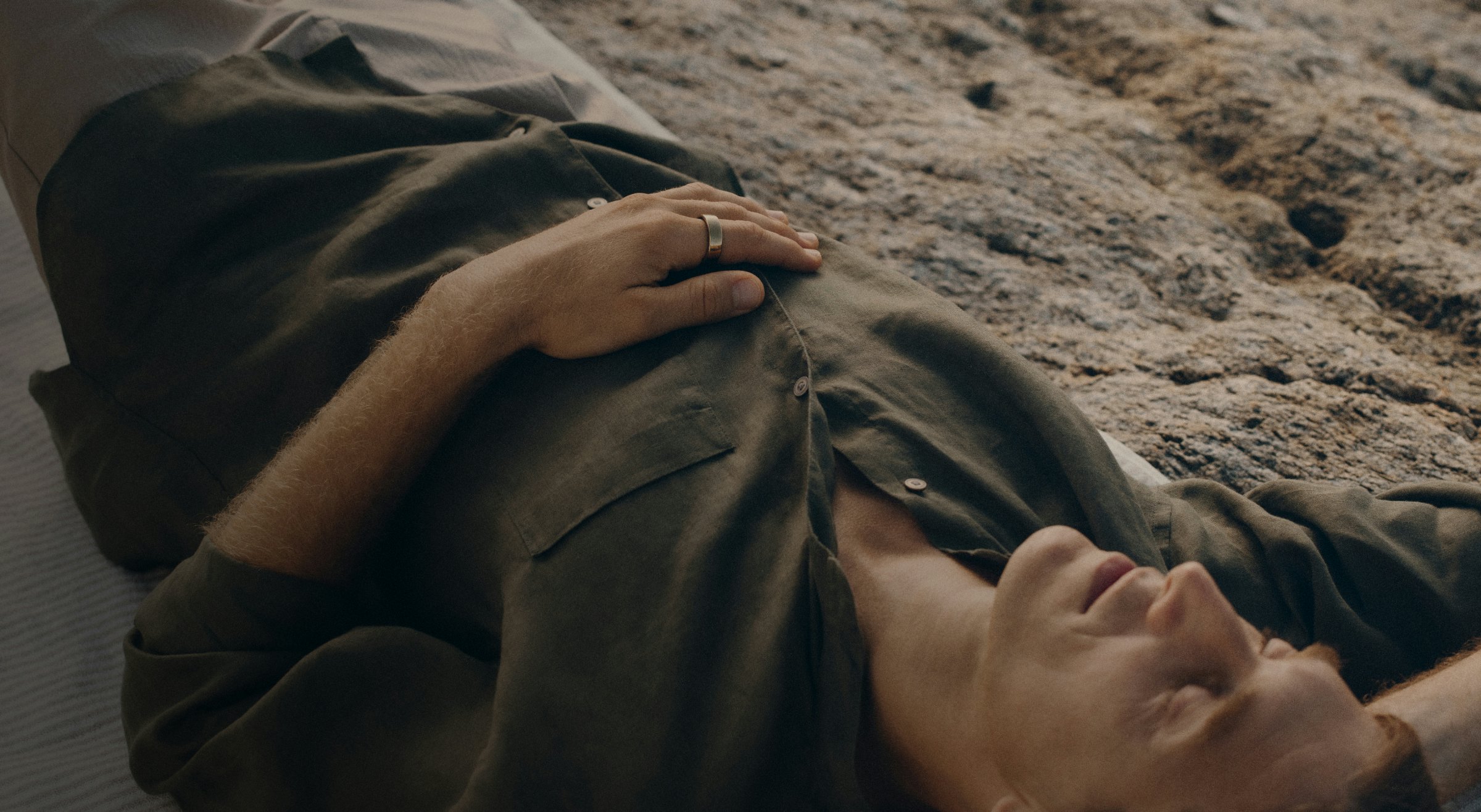 Man lying on the beach wearing his Oura ring