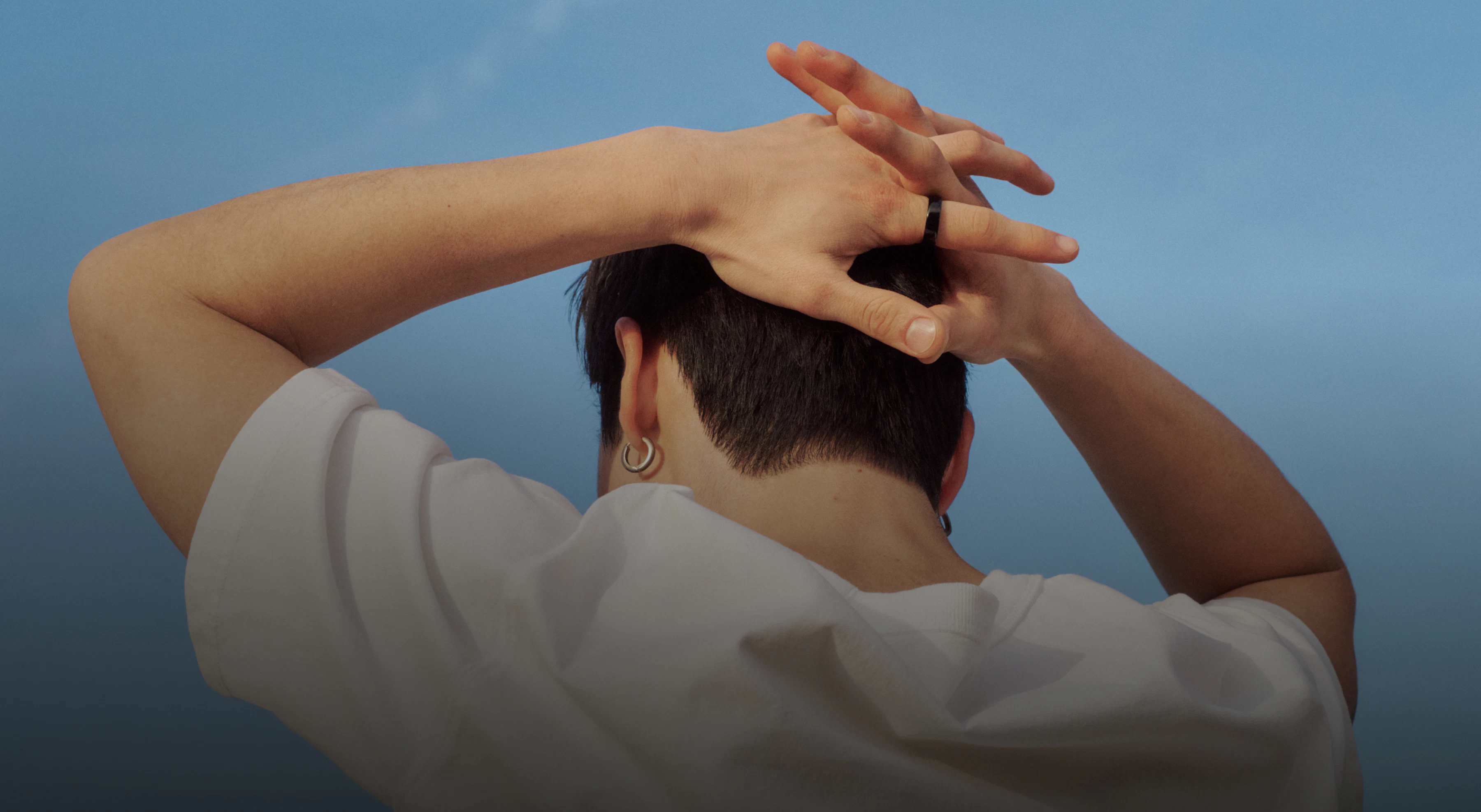 Person with their fingers interlaced behind their head wearing an Oura Ring 5