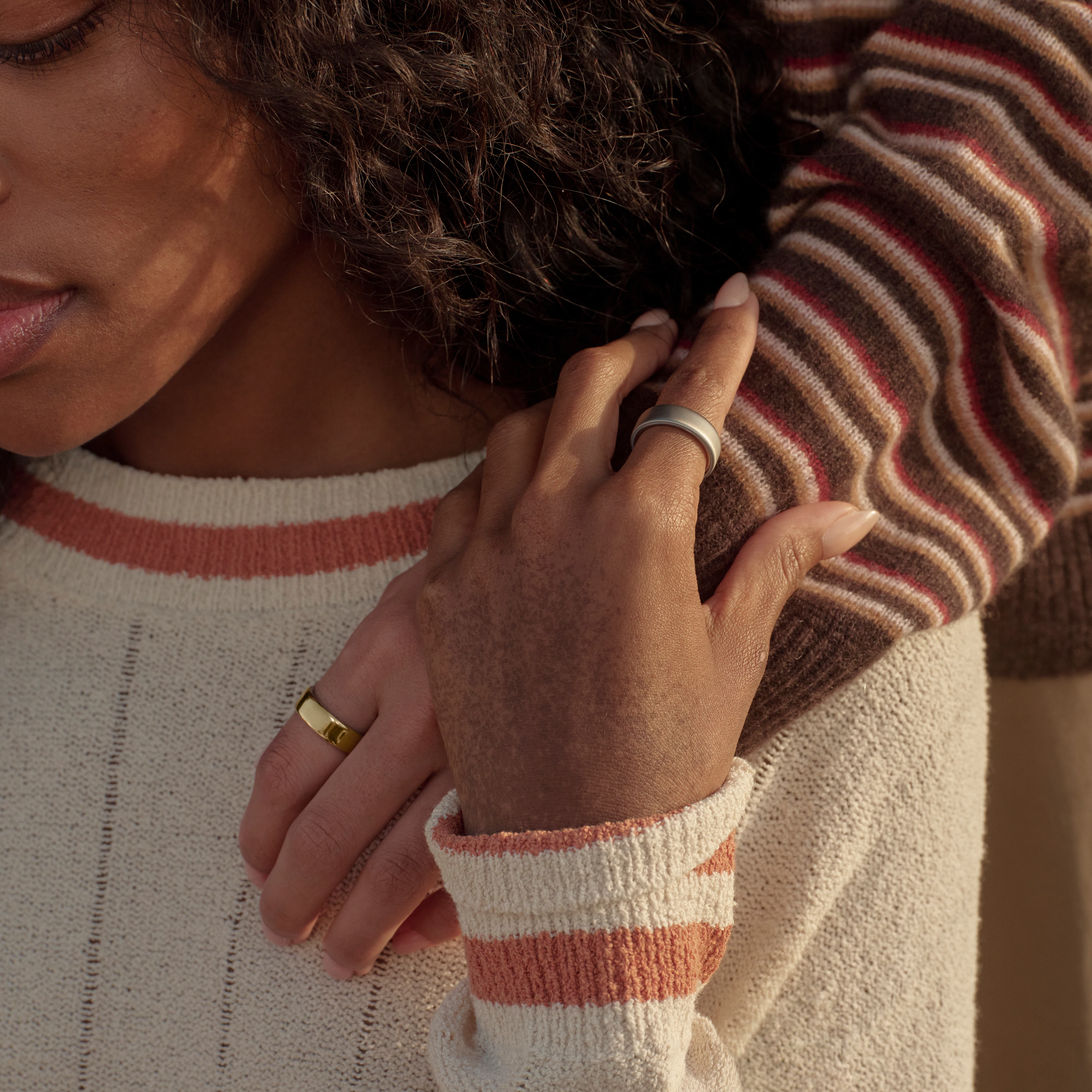 Oura Ring 5を着用している2人の人物のクローズアップ画像。一人の手が、もう一人の人物の肩に置かれている。