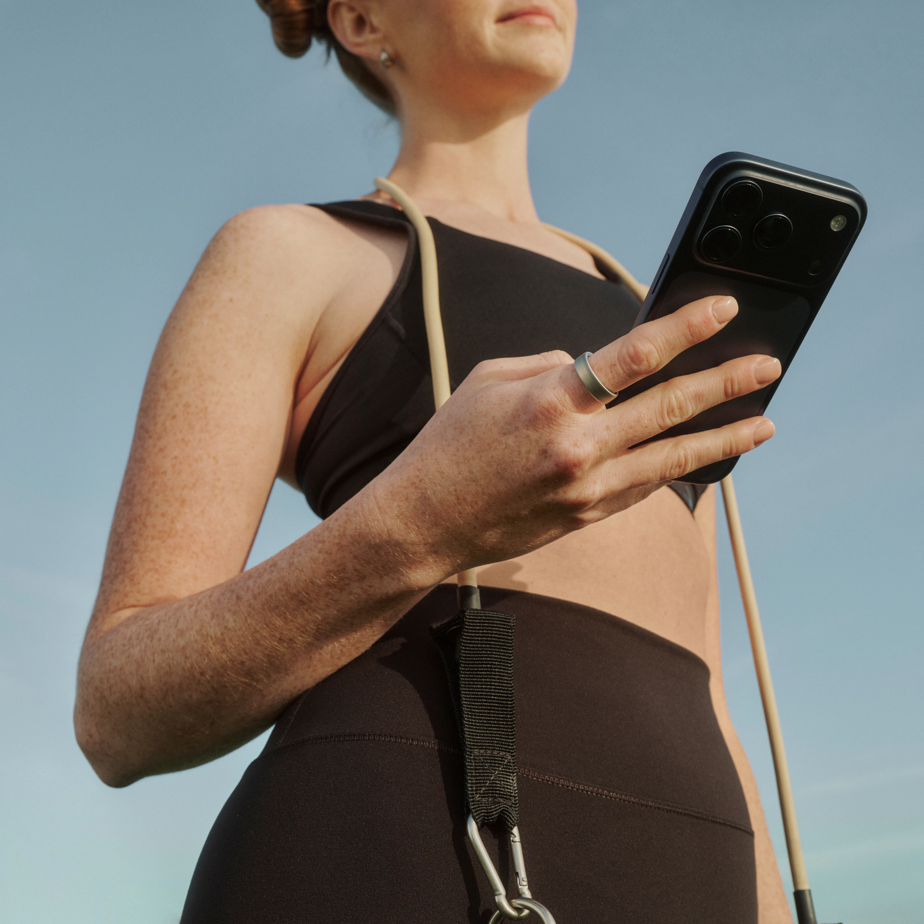屋外で、スマートフォンを持った手にOura Ring 5を着用している人物