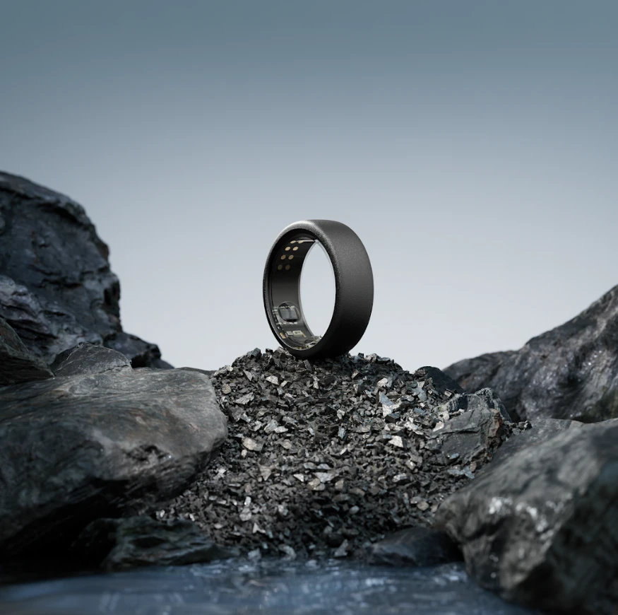 An Oura Ring in the Stealth finish standing on a mound of crushed slate