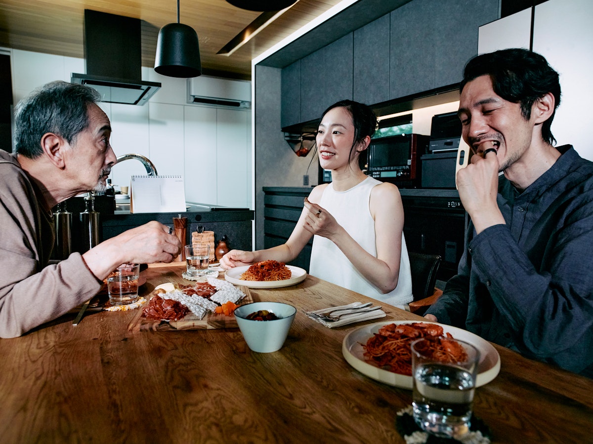 キッチンテーブルで食事をしているOura Ringを着用した3人の人物。