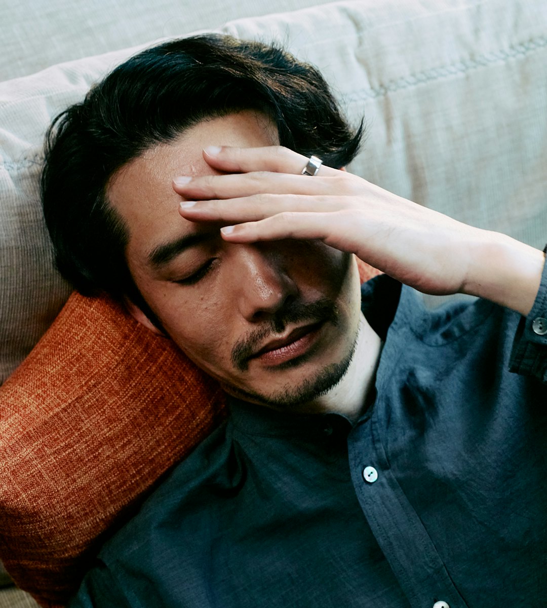 額に手を当てている人差し指にOura Ringを着用した男性。