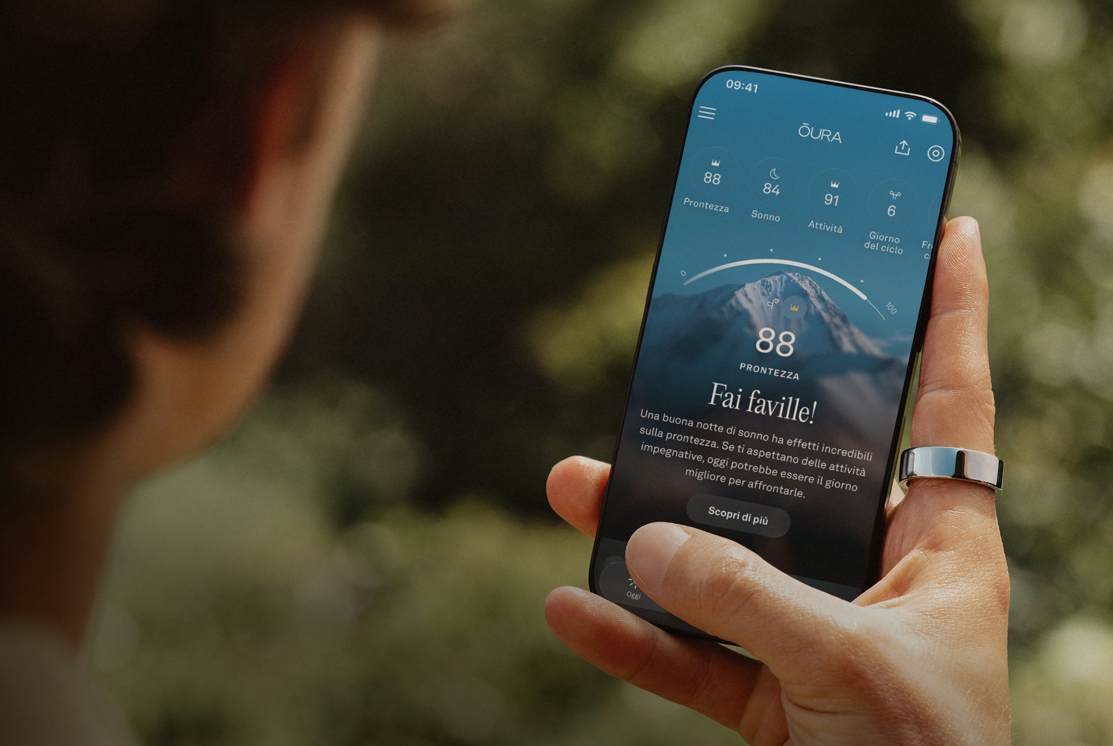 Persona che guarda Oura App sullo schermo del suo smartphone e indossa un Oura Ring sull'indice della mano destra