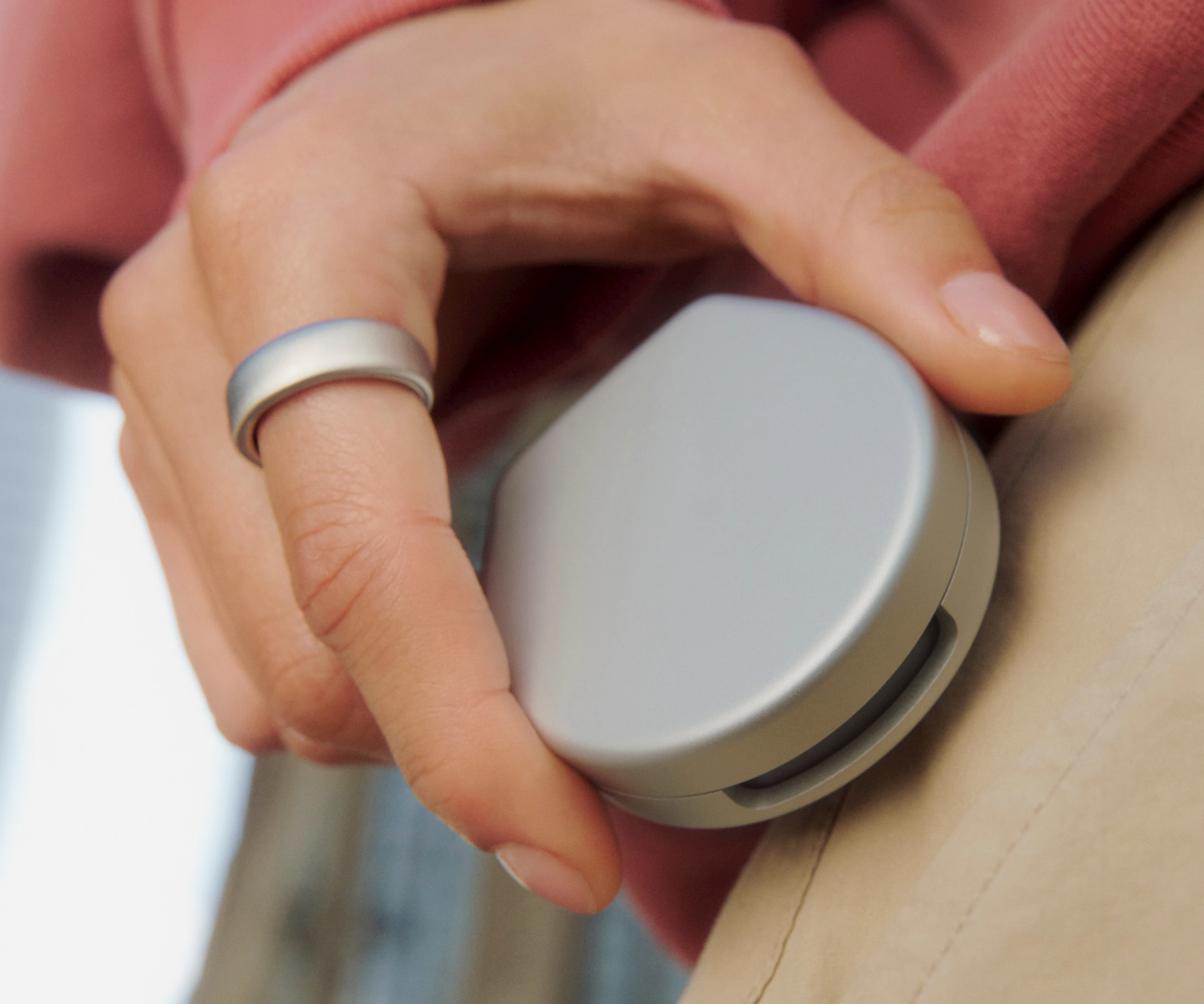 A close-up image of a closed Oura Ring 5 Charging Case in a hand