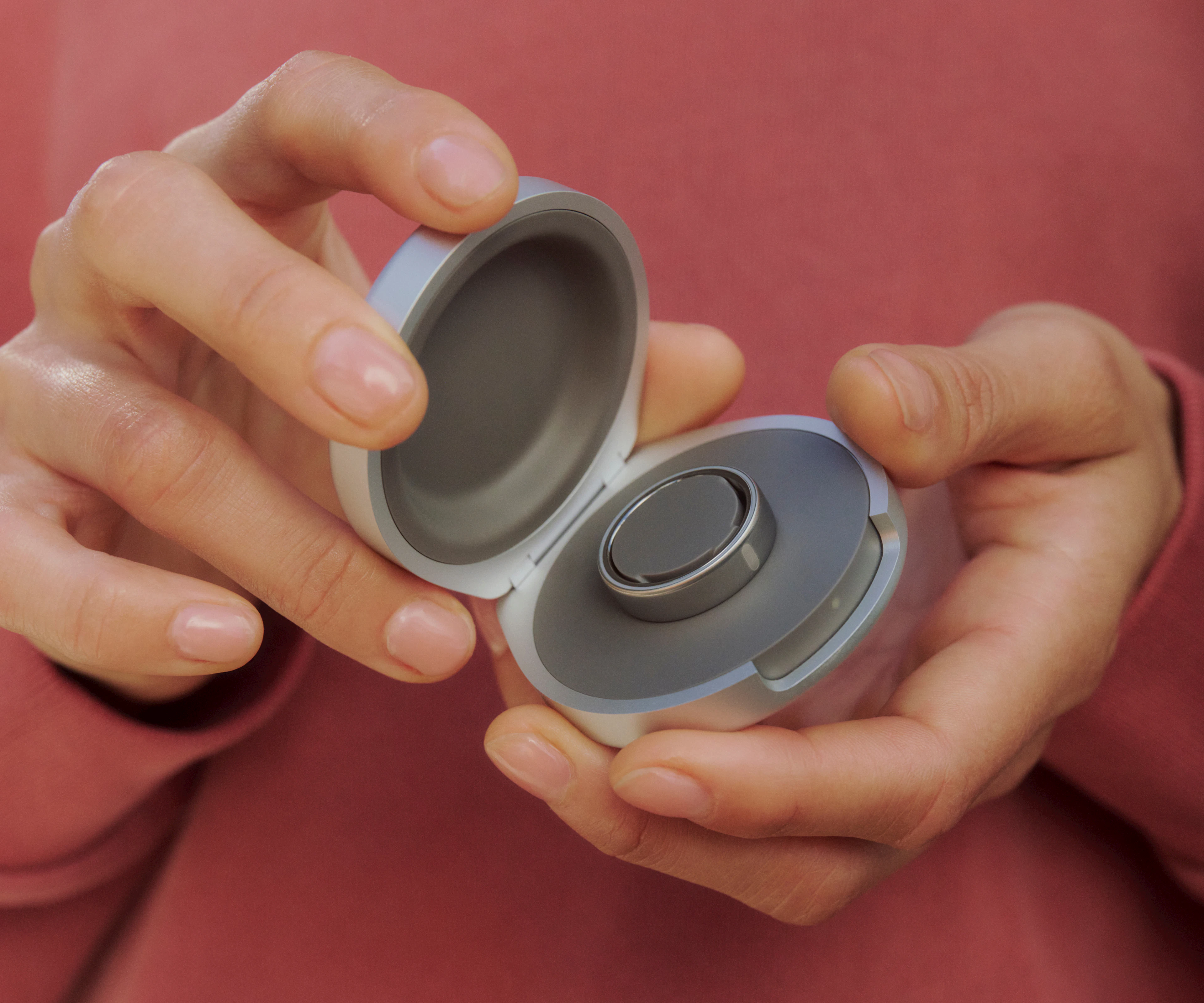 A close-up image of an open Oura Ring 5 Charging Case held in hands