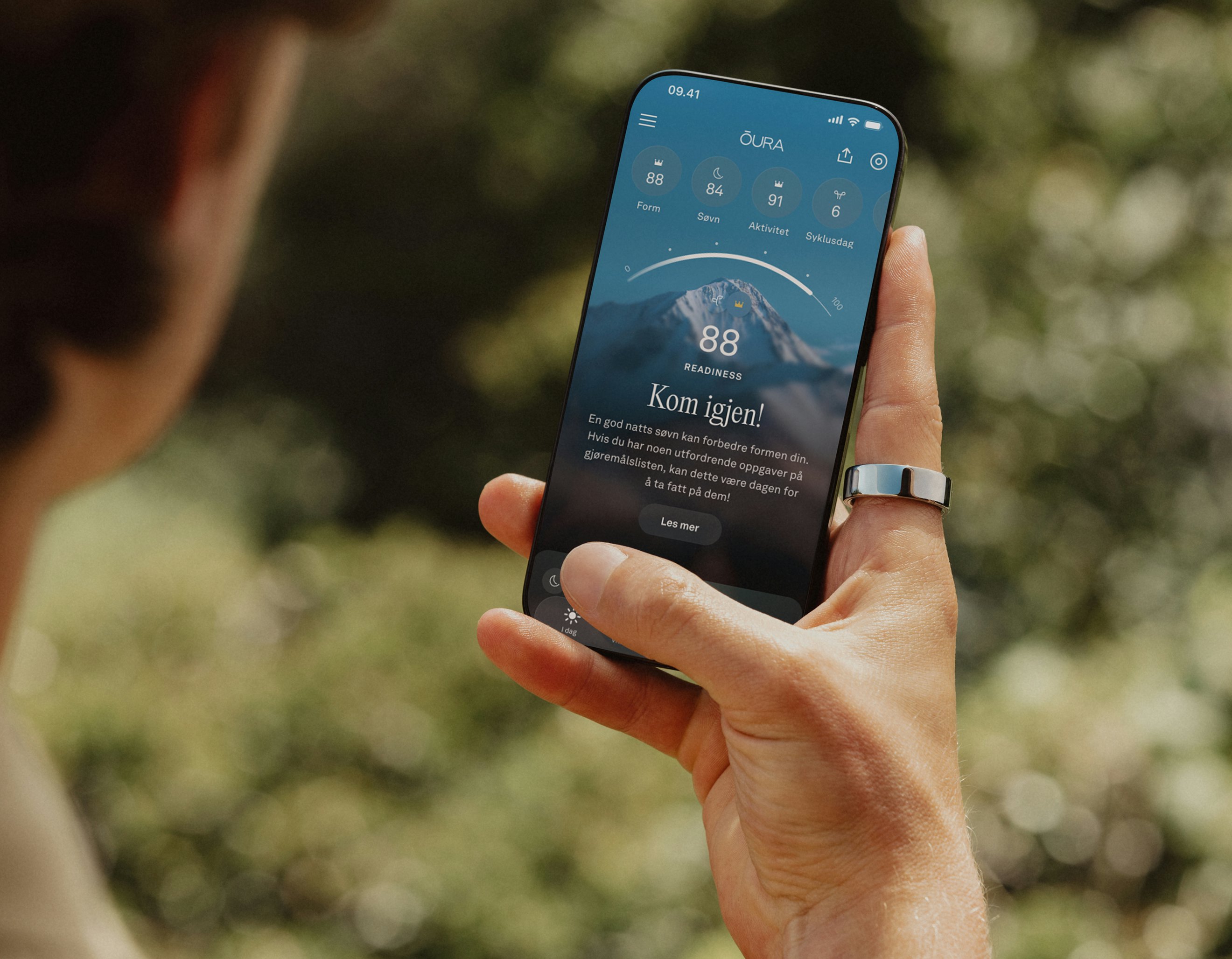 En person ser på Oura-appen på smarttelefonen sin mens hun har på seg en Oura Ring på høyre pekefinger