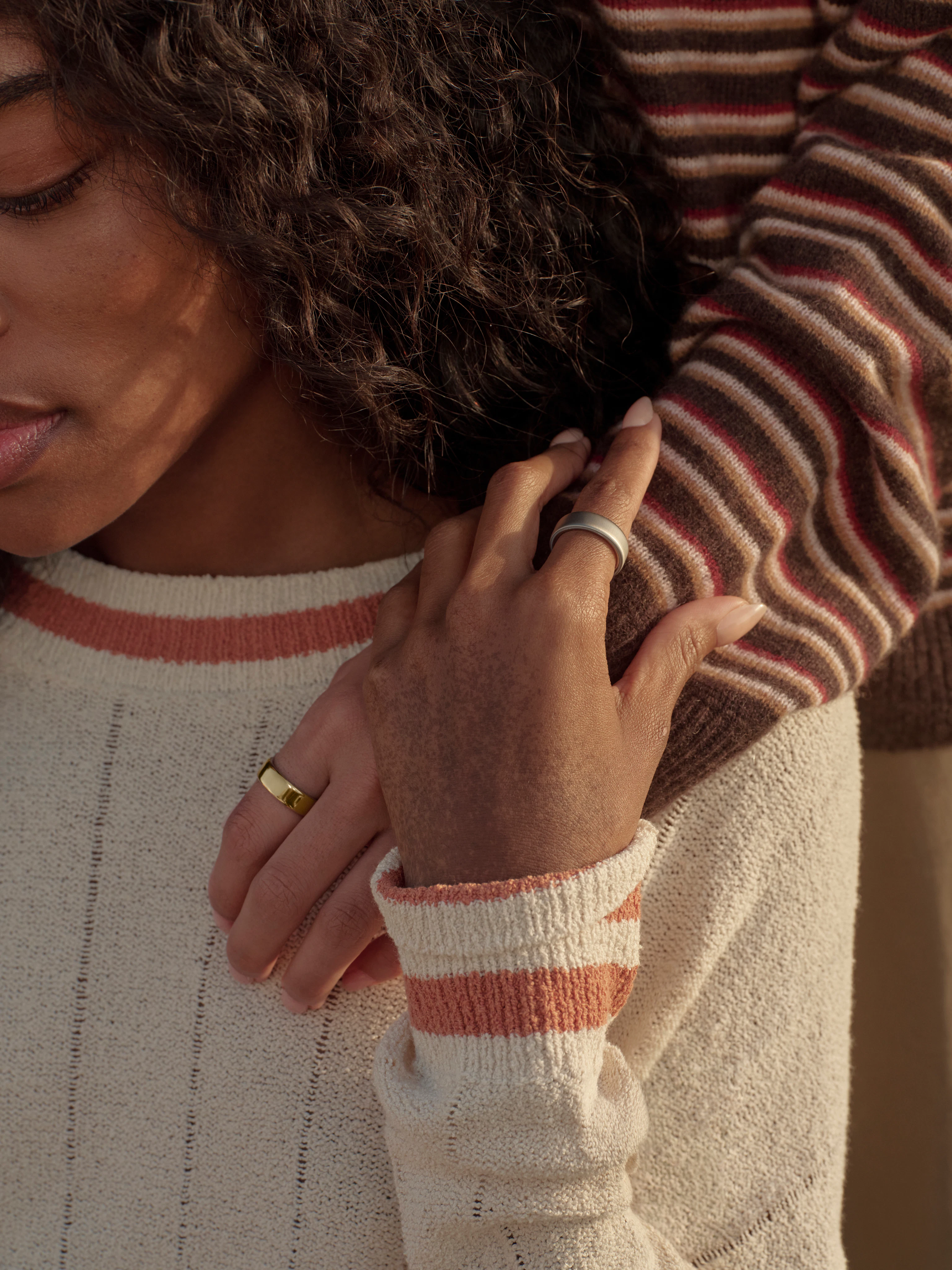 Woman in striped sweater with Gold Oura Ring resting her hand gently on a loved one's shoulder.